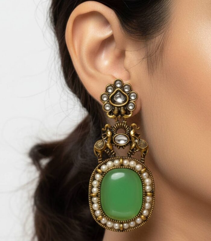 Shop antique elephant motif apple green stone earrings with pearl detailing and kundan accents. Perfect for weddings, festive wear and ethnic outfits. Premium quality imitation jewellery with antique gold finish.